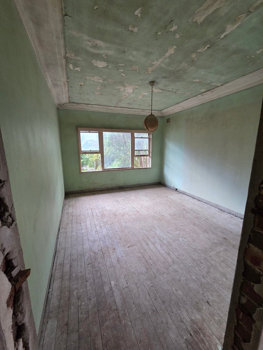 Restored bedroom with bare timber floorboards after clearing ceiling-high hoarding and stripping ruined carpet