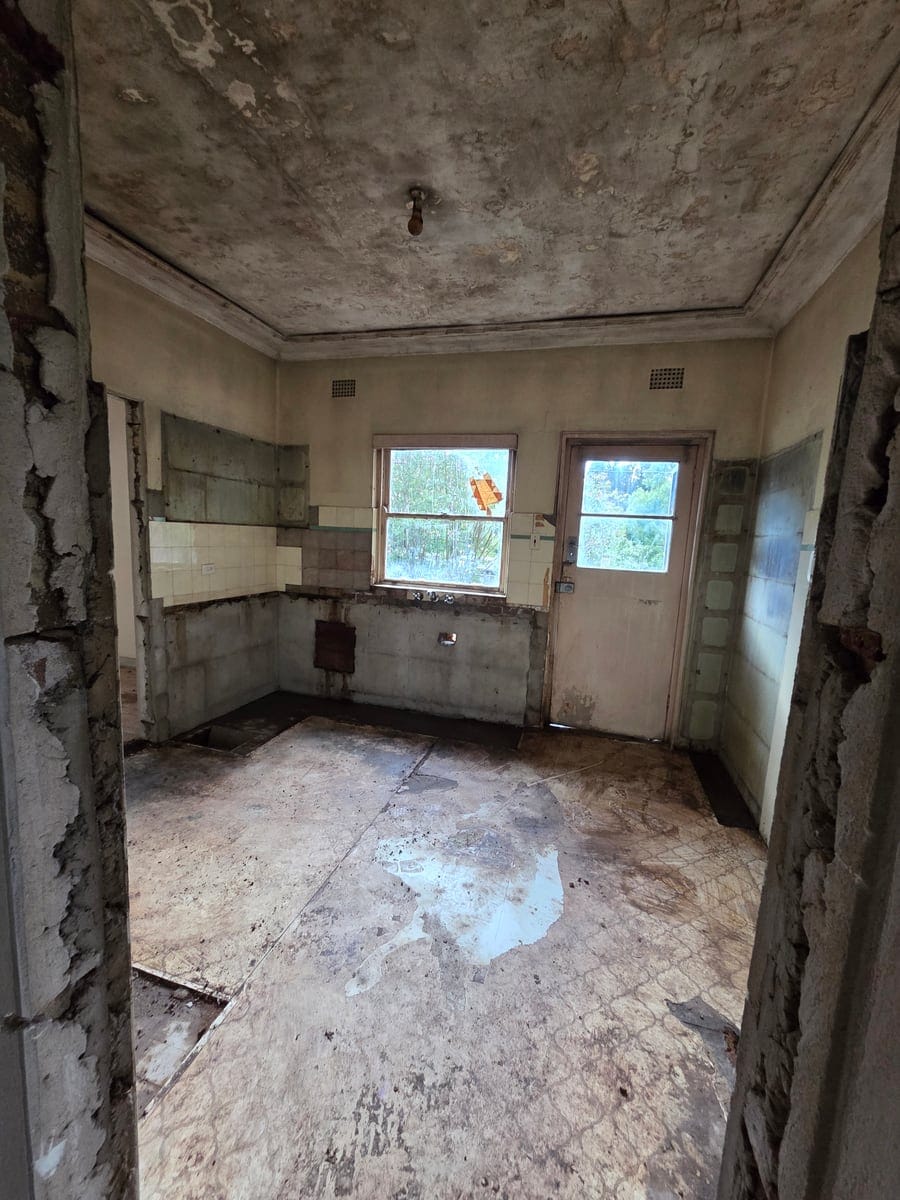 Demolished and stripped-out kitchen shell after removing rotted and fire-damaged cabinetry and wall linings